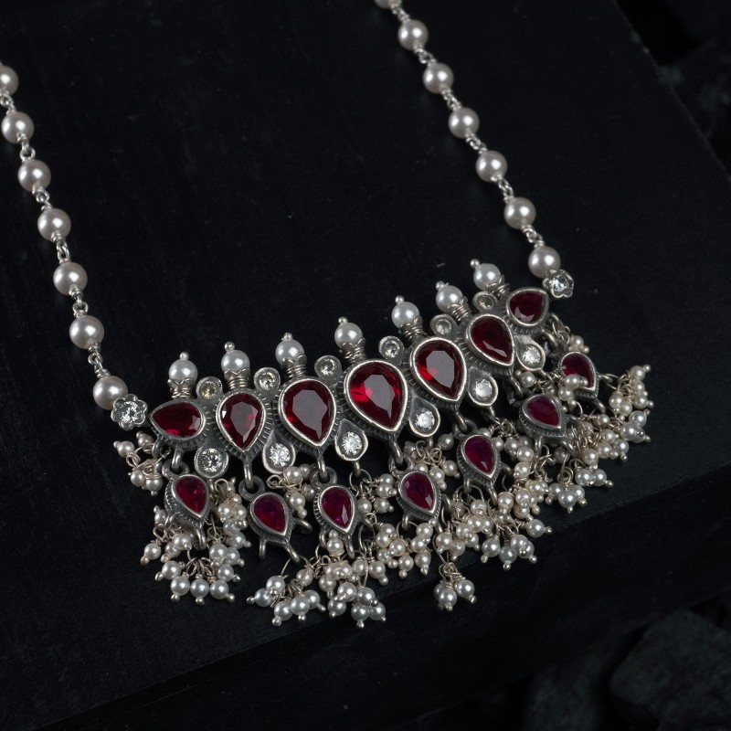 a silver tanmani pendant with red emrald stones and freshwater pearls.