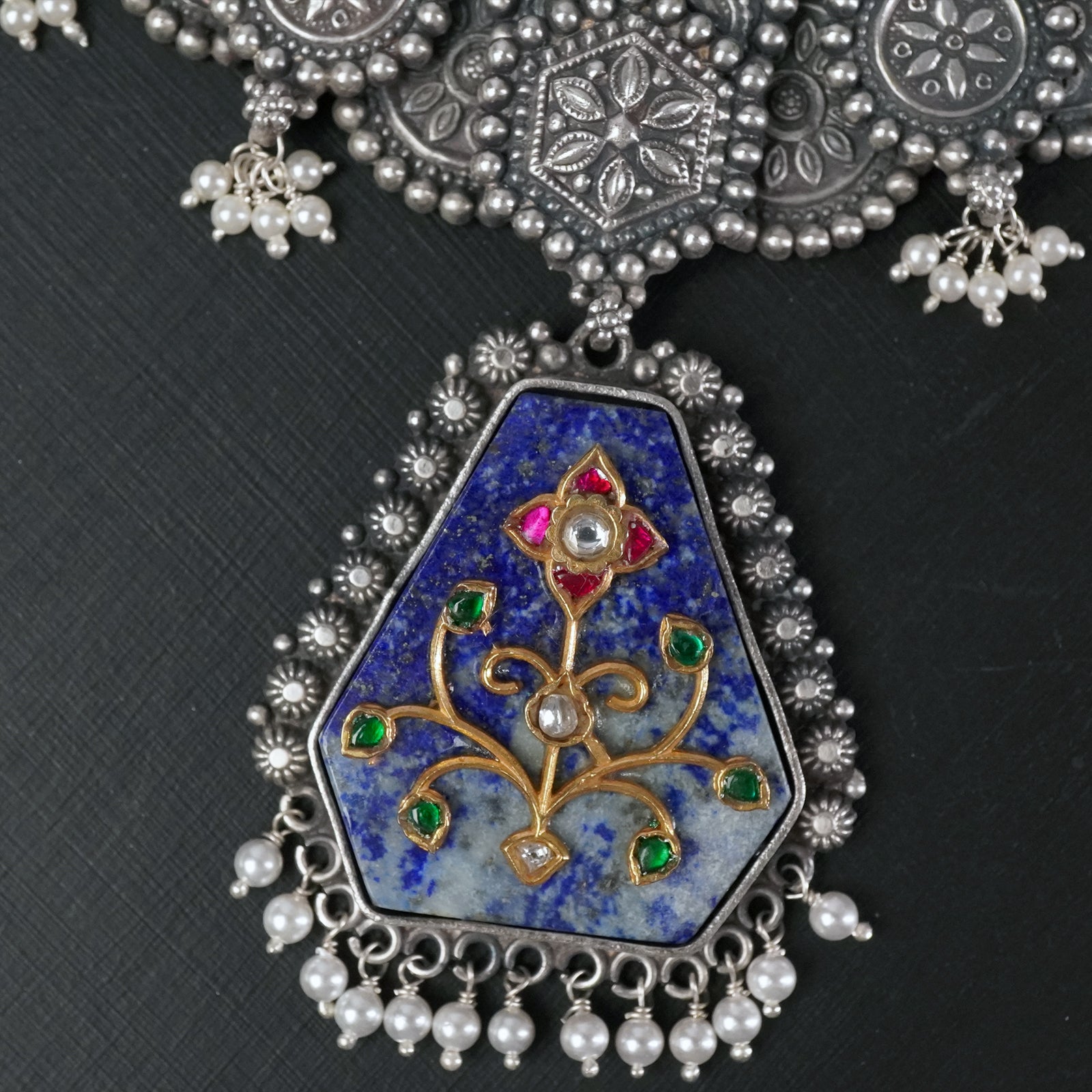 closeup of handmade silver pendant with kundan filigree work