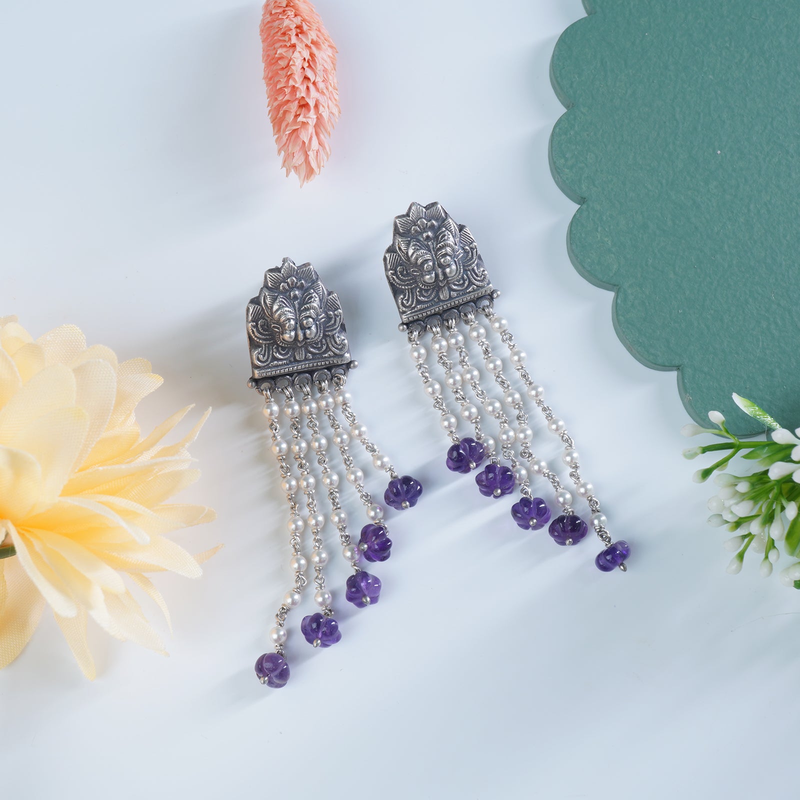 a pair of silver earrings with intricate handwork and a waterfall pearls pattern