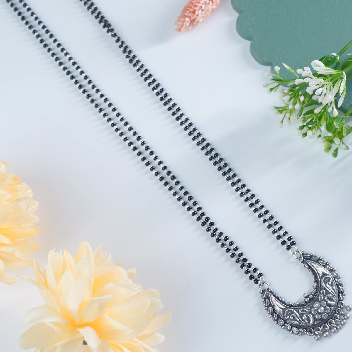 a closeup of silver mangalsutra design with chandrakor pendant.