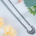 a closeup of silver mangalsutra design with chandrakor pendant.