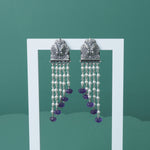 a photo of silver earrings studded with pearls and amethyst beads on a stand