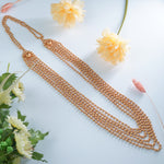 Gold beaded necklace on a light blue background with flowers