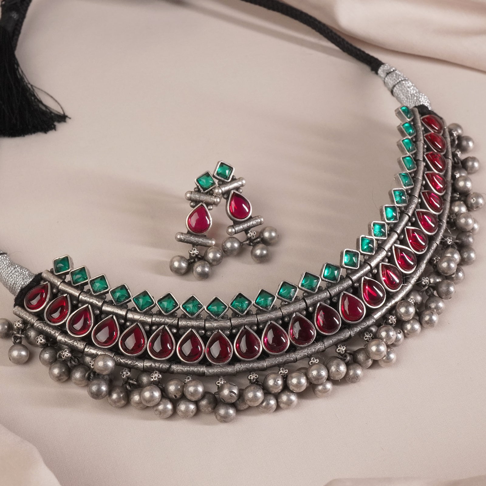 a wide angle shot of silver kolhapuri necklace design with red and green kemp stones